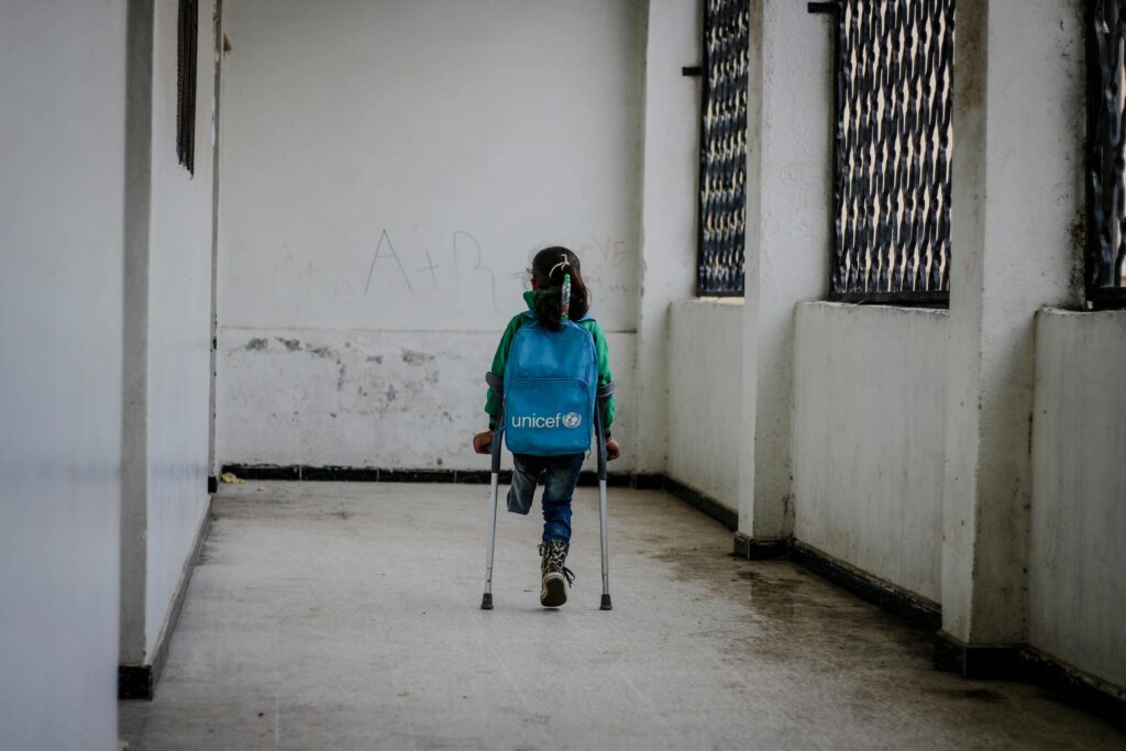 Syyrialainen lapsi, jolla kävelykepit ja sininen Unicef-reppu