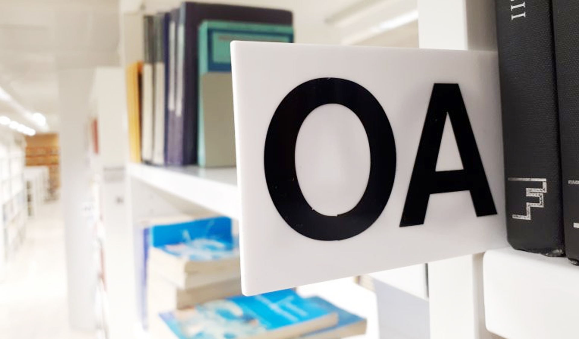 Kirjahylly jossa kirjojen välissä on teksti OA