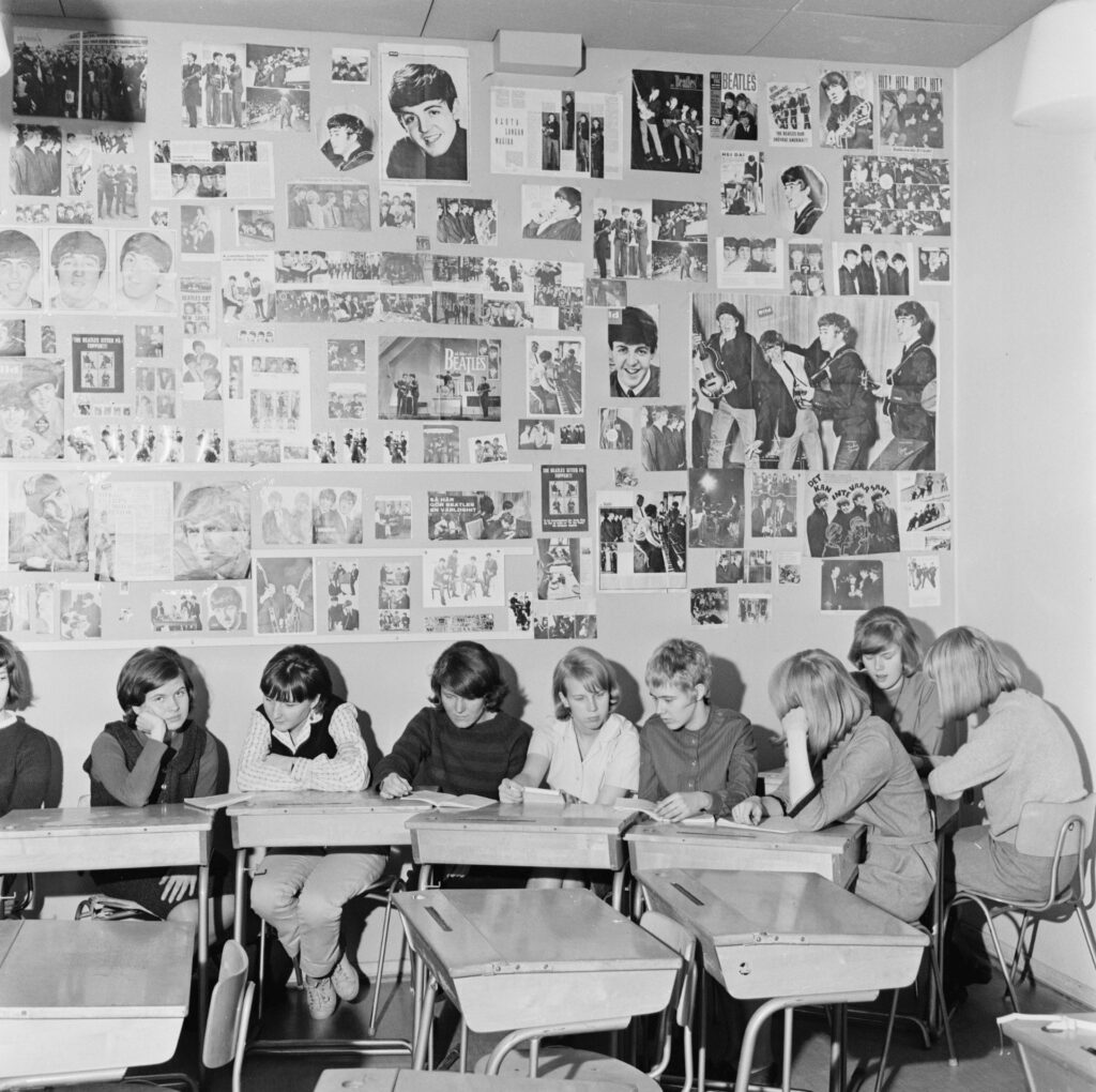 Beatles-faneja, joiden takana olevalla seinällä on runsaasti Beatles-julisteita.